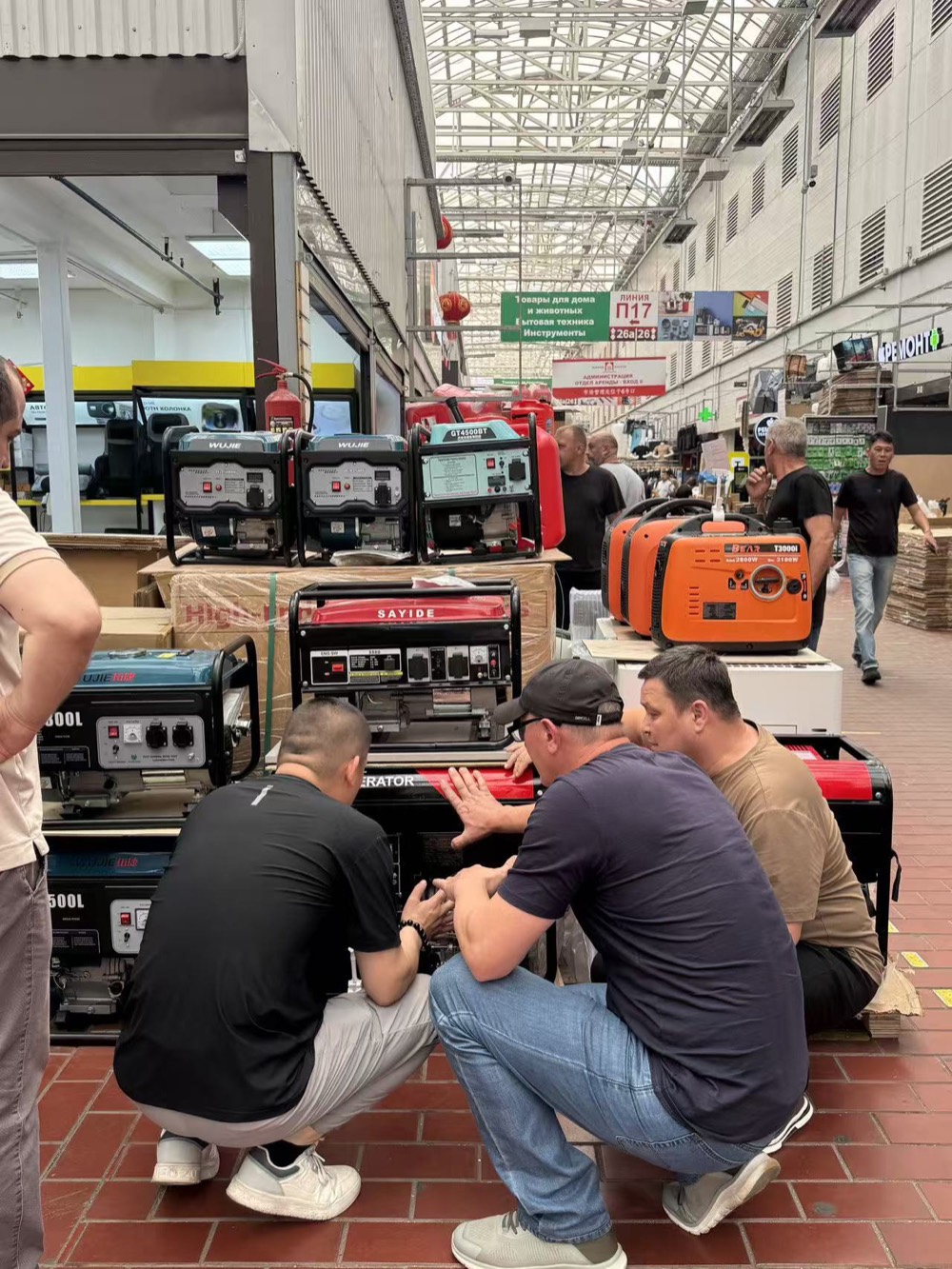 Portable generators displayed while several visitors inspect equipment at a Russian retail market